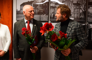 radny Krzysztof Pabich (z prawej) wręcza kwiaty autorowi wystawy