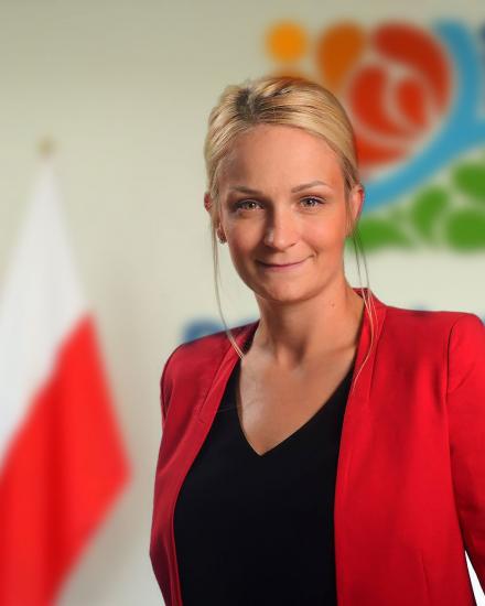 Emilia Załachowska - zdjęcie przedstwia kobiete o blond włosach w czerwonym żakiecie
